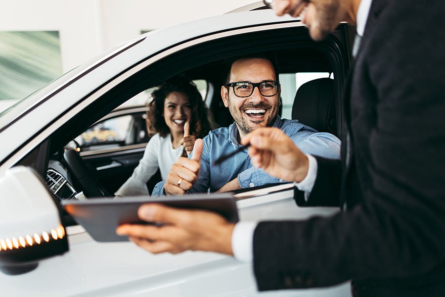 couple in car with salesman holding keys